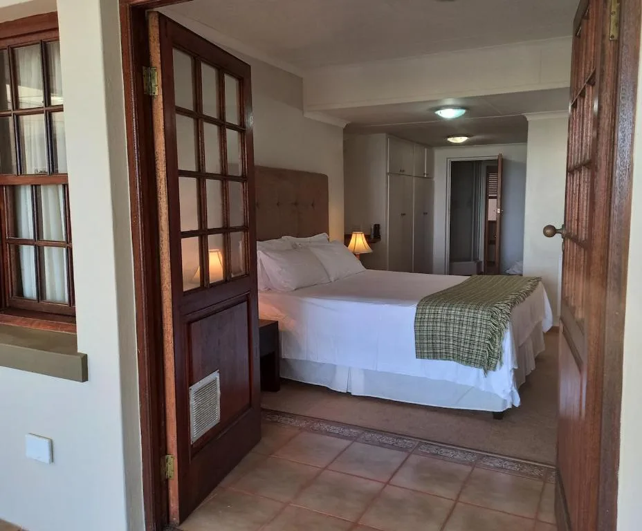 Spacious bedroom with queen bed, wooden doors, and built-in wardrobe