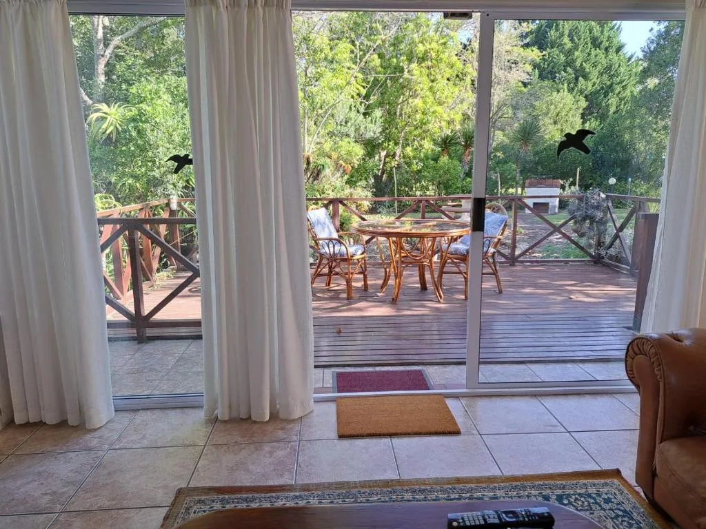 Wooden deck with dining furniture and lush garden views beyond
