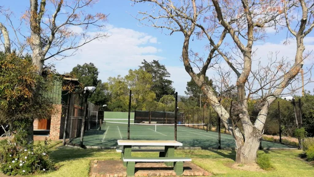 Picnic table and tennis court surrounded by mature trees on property grounds