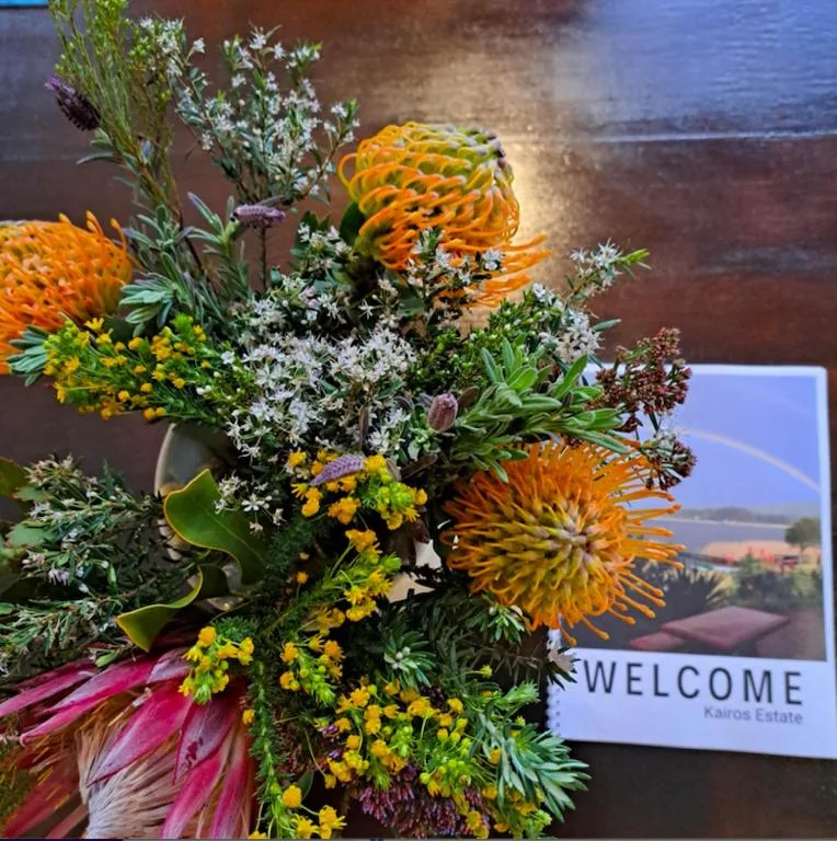 Colorful welcome flower arrangement with orange proteas and yellow blooms