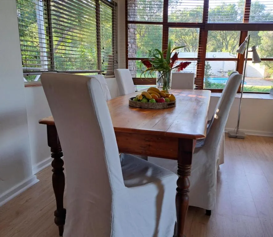 Wooden dining table with cream upholstered chairs and fruit centerpiece
