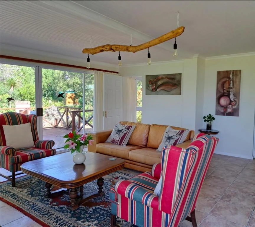 Spacious lounge with leather sofa, striped armchairs, wooden branch chandelier