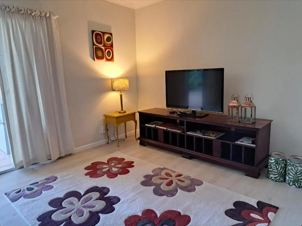 Modern living room with television, dark entertainment unit, and decorative rug