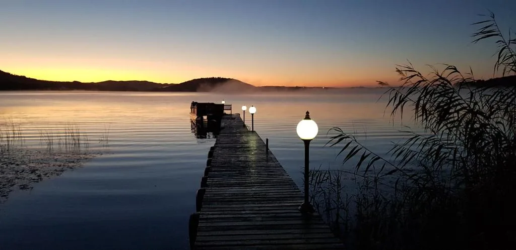 Twilight view across calm lake with wooden jetty and mountains