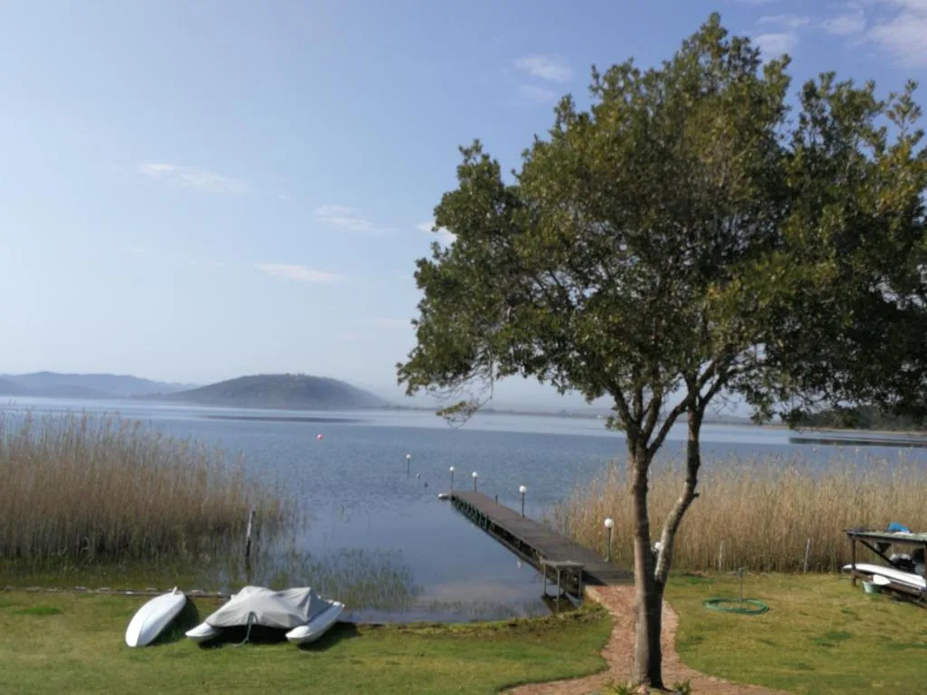 Scenic lagoon view with moored boats, reeds, and distant hills