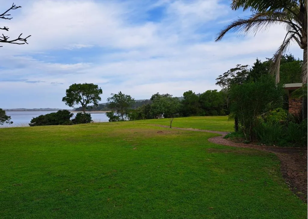 Expansive lake view across manicured gardens with distant forested shoreline