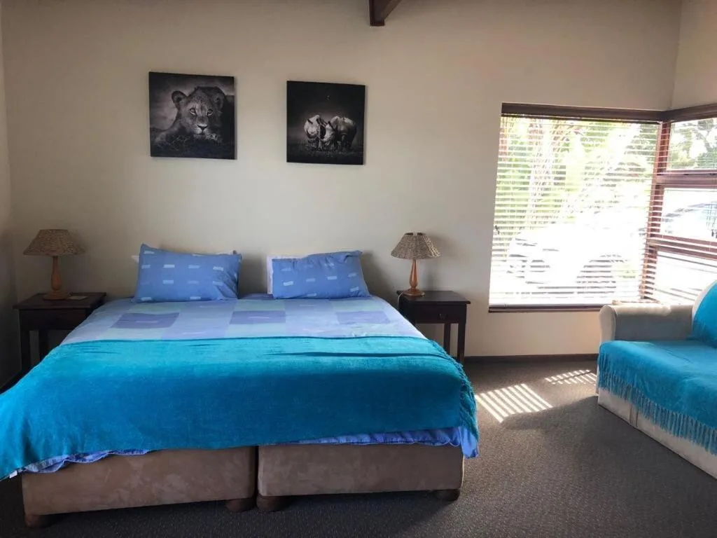 Bright bedroom with blue bedding, twin beds, wildlife artwork, and garden views