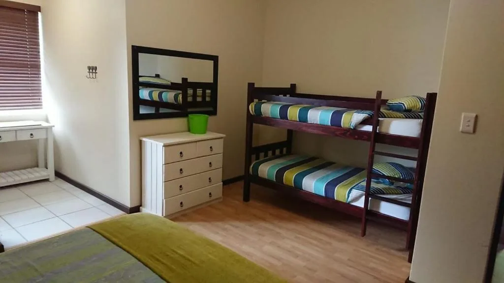 Bedroom with bunk beds, wooden dresser, and natural window light