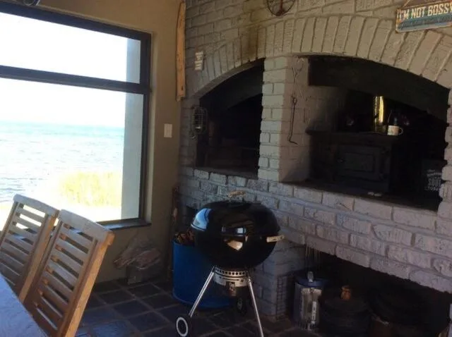 Braai area with grill overlooking tranquil lake waters through large window