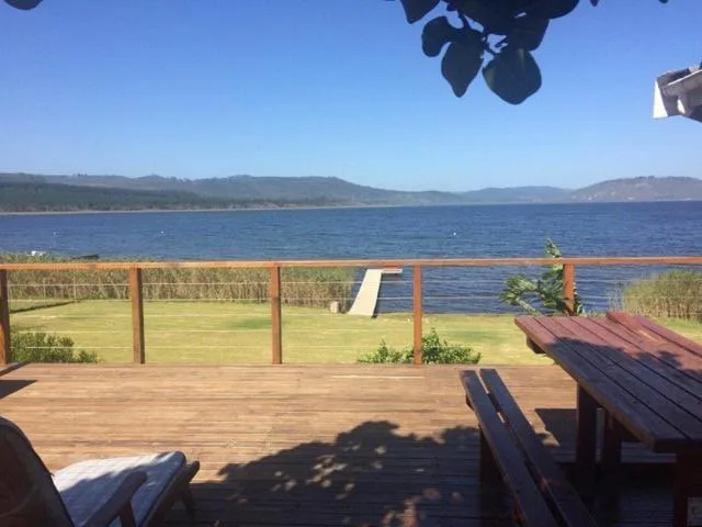 Wooden deck with lake view, lounge chairs, and mountain backdrop