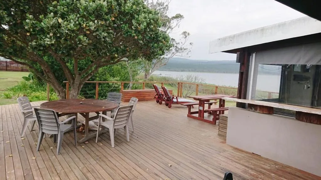 Wooden deck with outdoor dining and seating, overlooking lagoon water