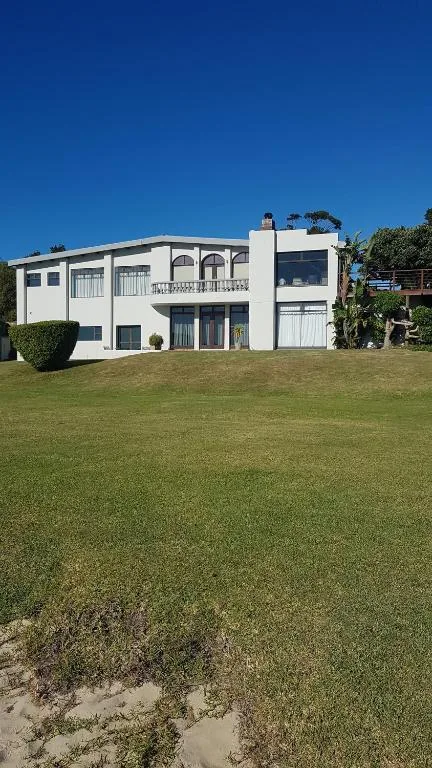 White modern two-story house with manicured lawn and clear blue sky