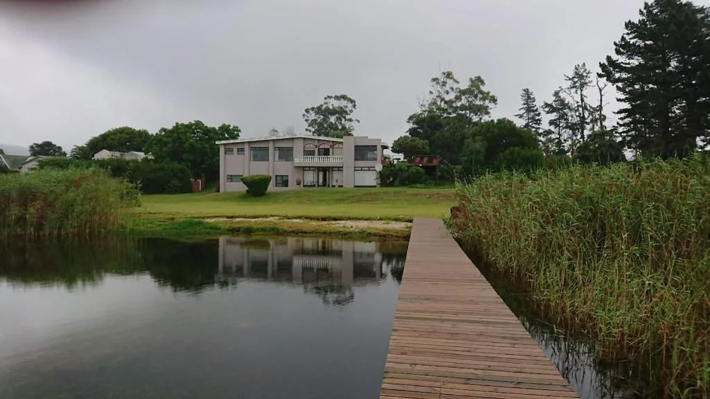 Modern waterfront house with wooden deck overlooking lagoon and gardens