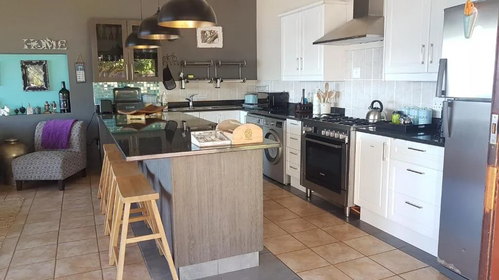Modern kitchen with island, stove, white cabinetry, pendant lights