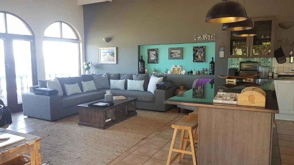 Spacious open-plan lounge with grey sofa, turquoise accent wall, and natural light