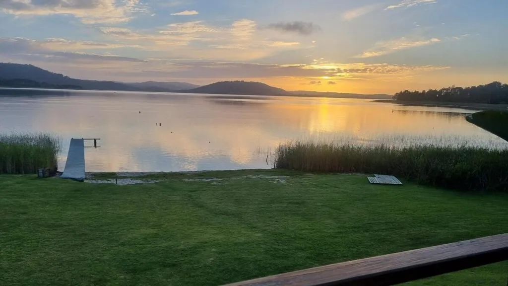 Sunset over Swartvlei Lake with mountains and grassy shoreline