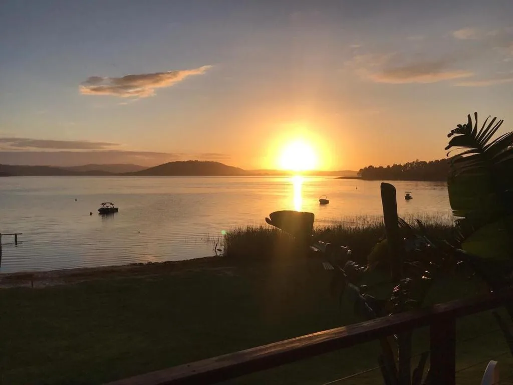 Golden sunset over calm lagoon with mountains and moored boats