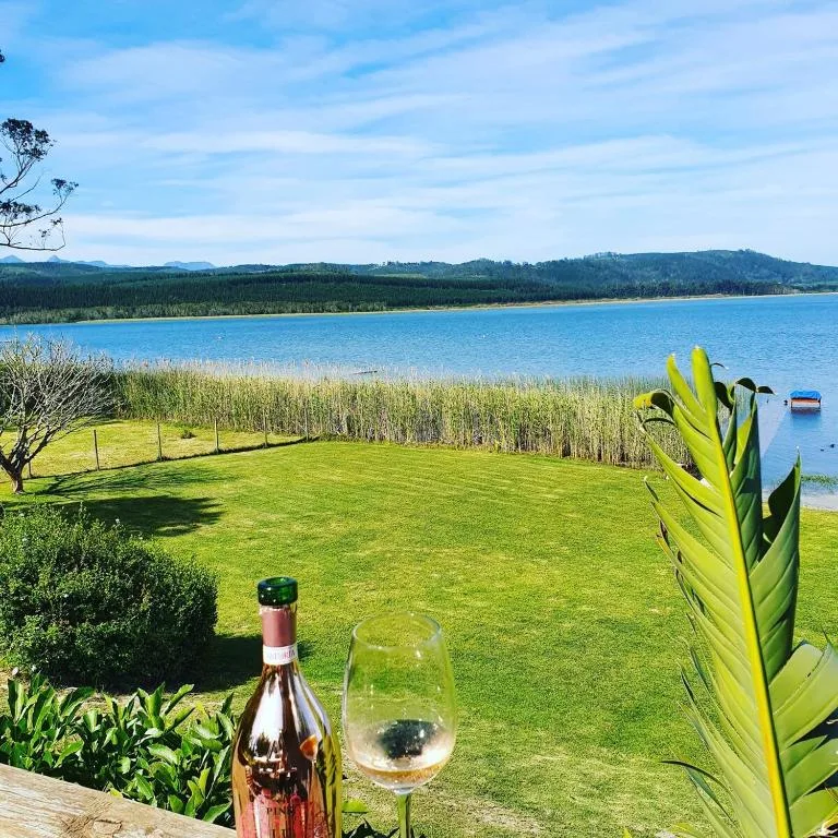 Scenic lake and mountain vista with manicured garden and wine glass