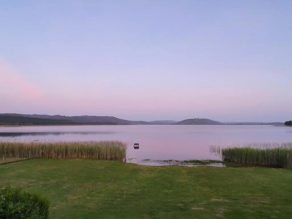 Serene lagoon sunrise with mountains and reed beds framing the water