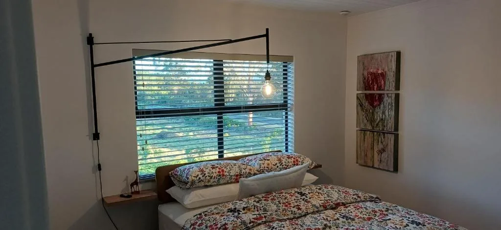 Spacious bedroom with twin beds, black metal frame, and garden views through shuttered windows