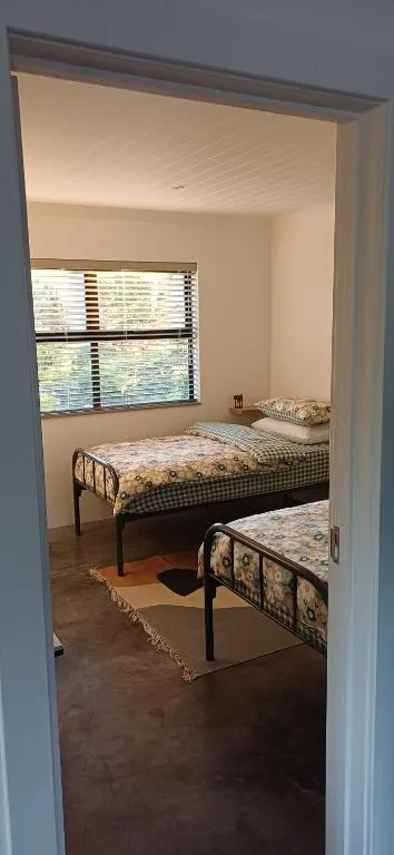Bright bedroom with two metal-framed beds and window blinds