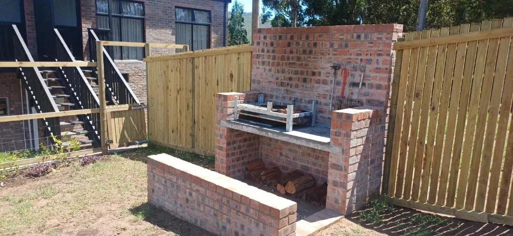 Brick braai area with wooden bench seating in fenced garden