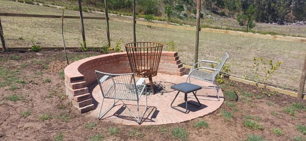 Brick fire pit seating area with metal chairs and small table outdoors