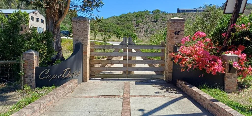 Driveway entrance with wooden gates and pink flowering shrubs
