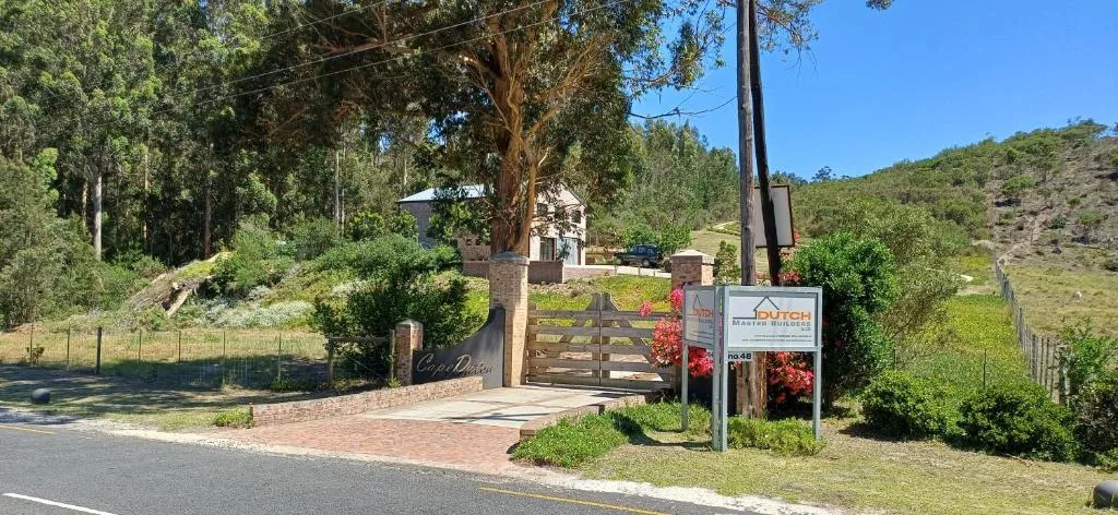 Property entrance with brick driveway, wooden gate, and lush garden surroundings