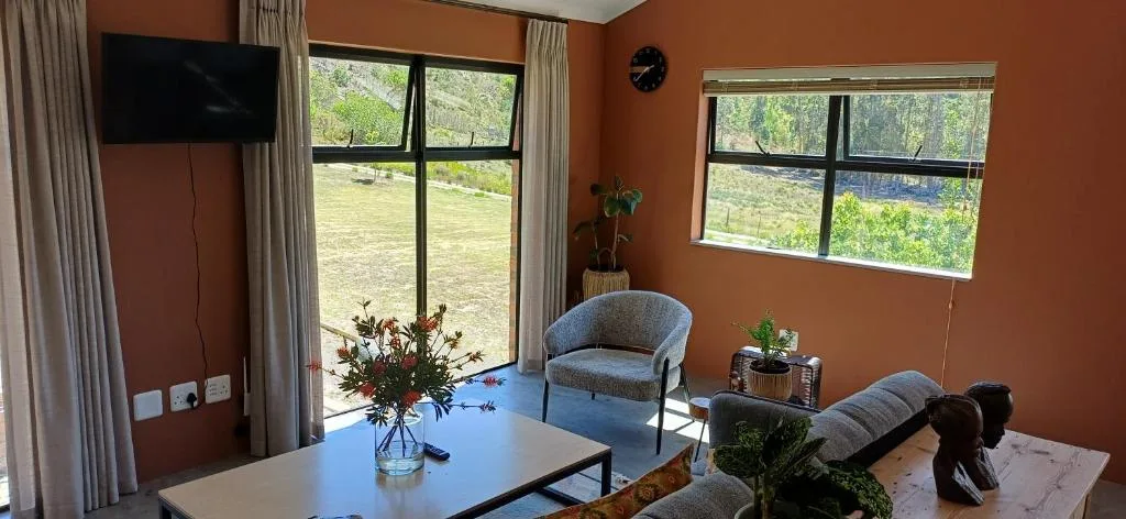 Spacious lounge with terracotta walls, TV, comfortable seating, and garden views