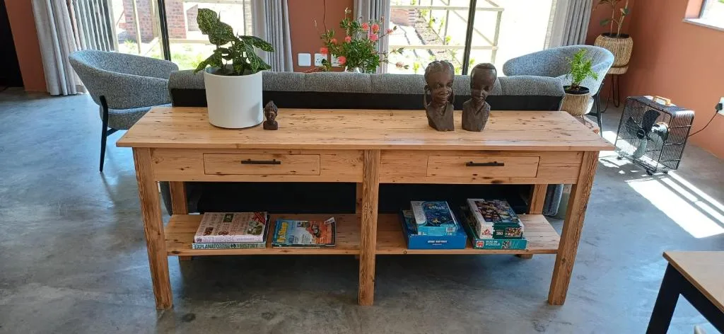 Spacious lounge with wooden console table, potted plants, and comfortable seating