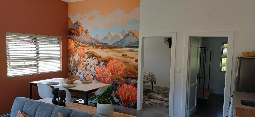 Living room with sofa, landscape mural, windows, and potted plants