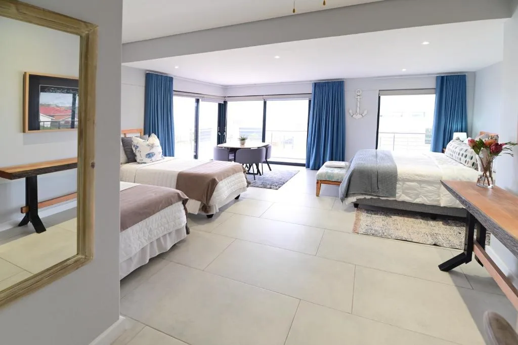 Spacious bedroom with multiple beds, ocean views, blue curtains