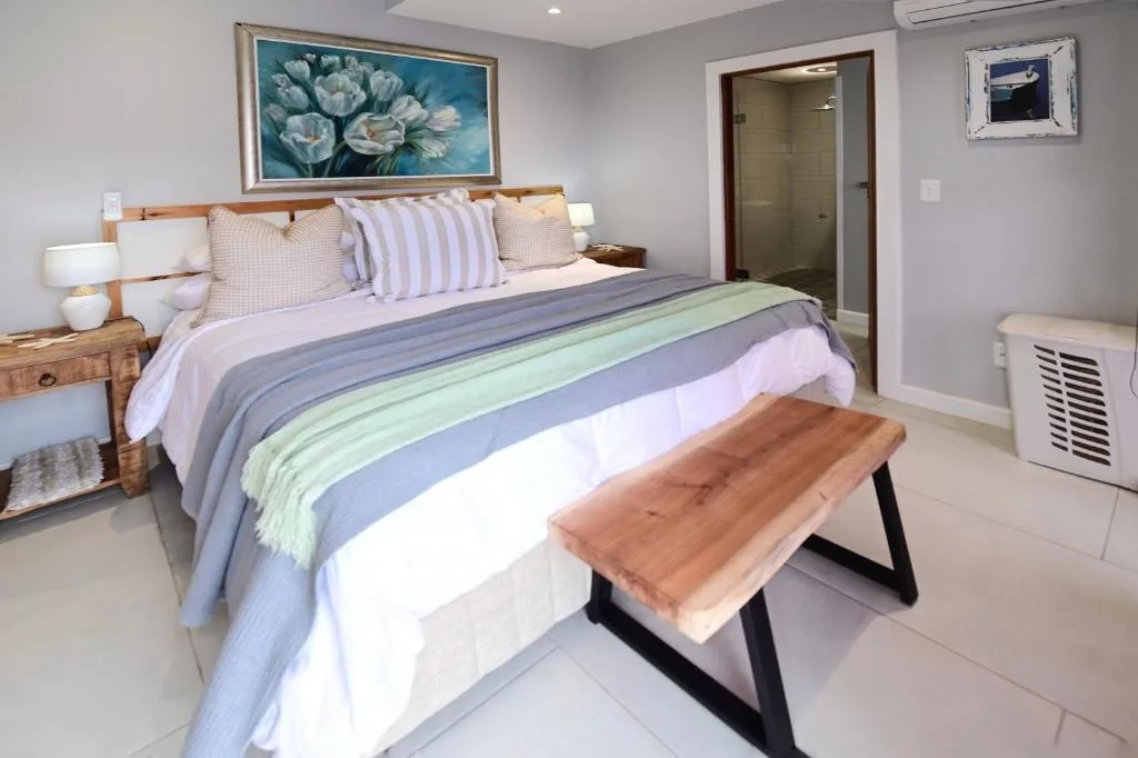 Bright bedroom with queen bed, striped bedding, wooden nightstands, and ensuite bathroom door