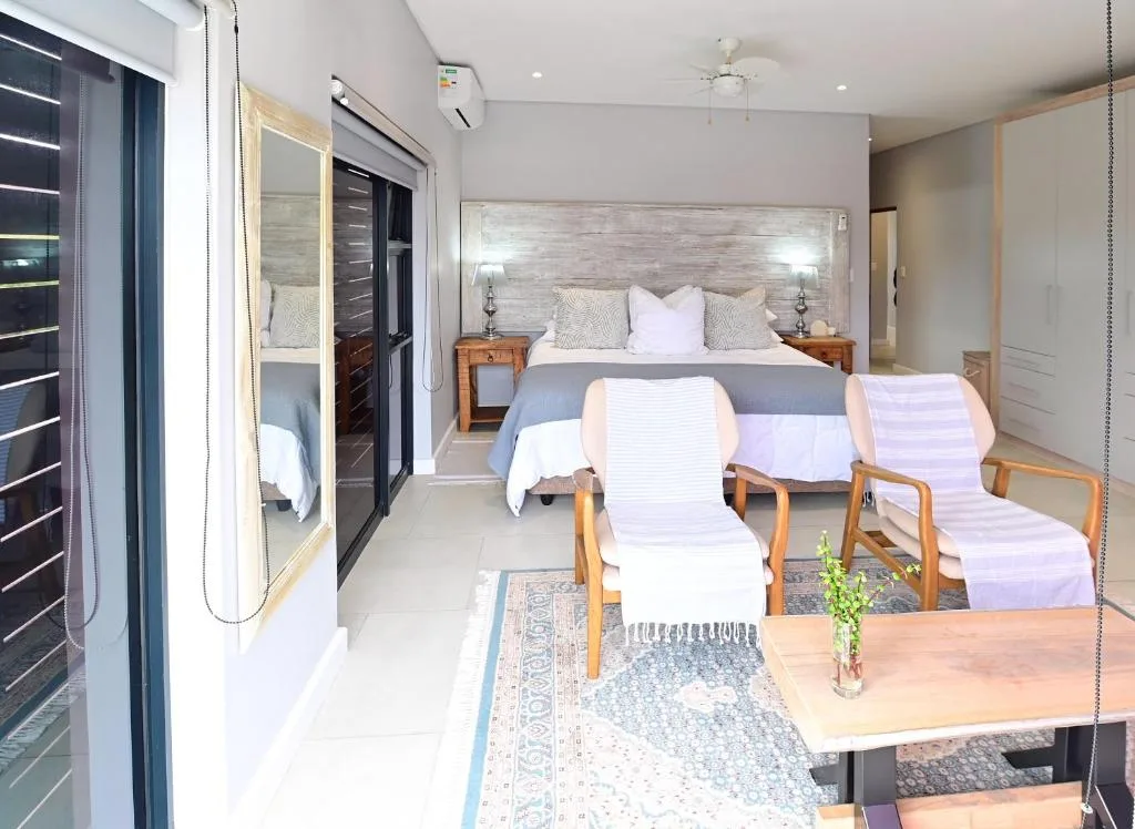 Spacious modern bedroom with queen bed, wooden nightstands, and seating area