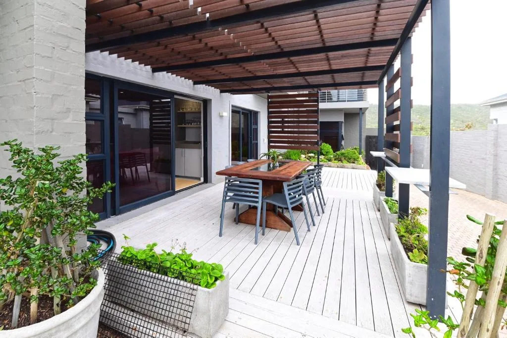Modern covered patio with wooden table, chairs, and lush planters
