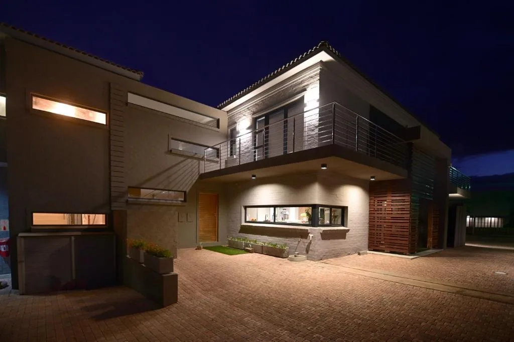 Modern two-story house at dusk with illuminated facade and paved driveway