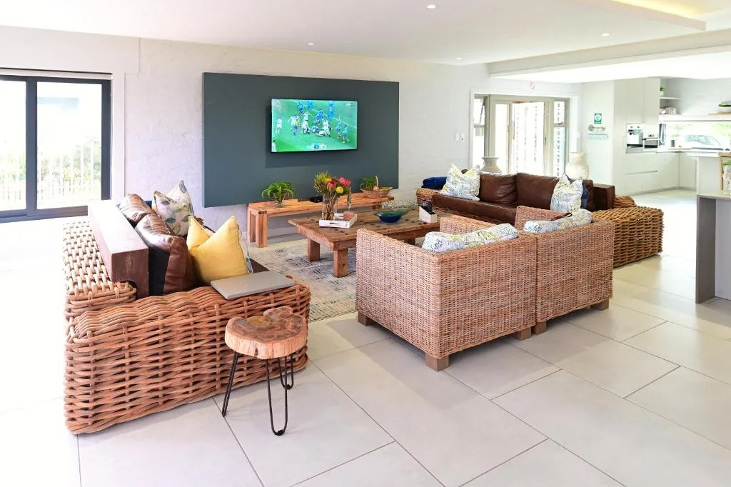 Spacious open-plan lounge with wicker furniture and wall-mounted TV