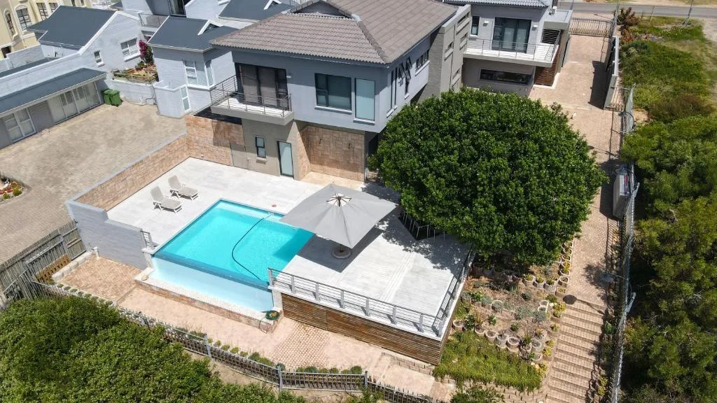 Aerial view of modern home with bright turquoise swimming pool and deck area