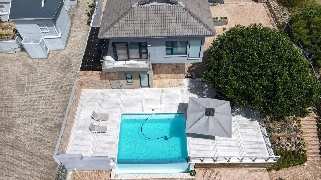 Aerial view of bright blue swimming pool with white deck and loungers