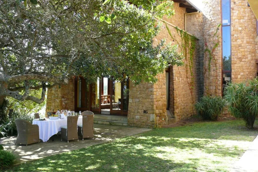 Outdoor dining area with table and chairs beside brick villa