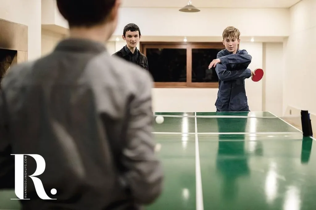 Children playing table tennis in bright indoor recreational room