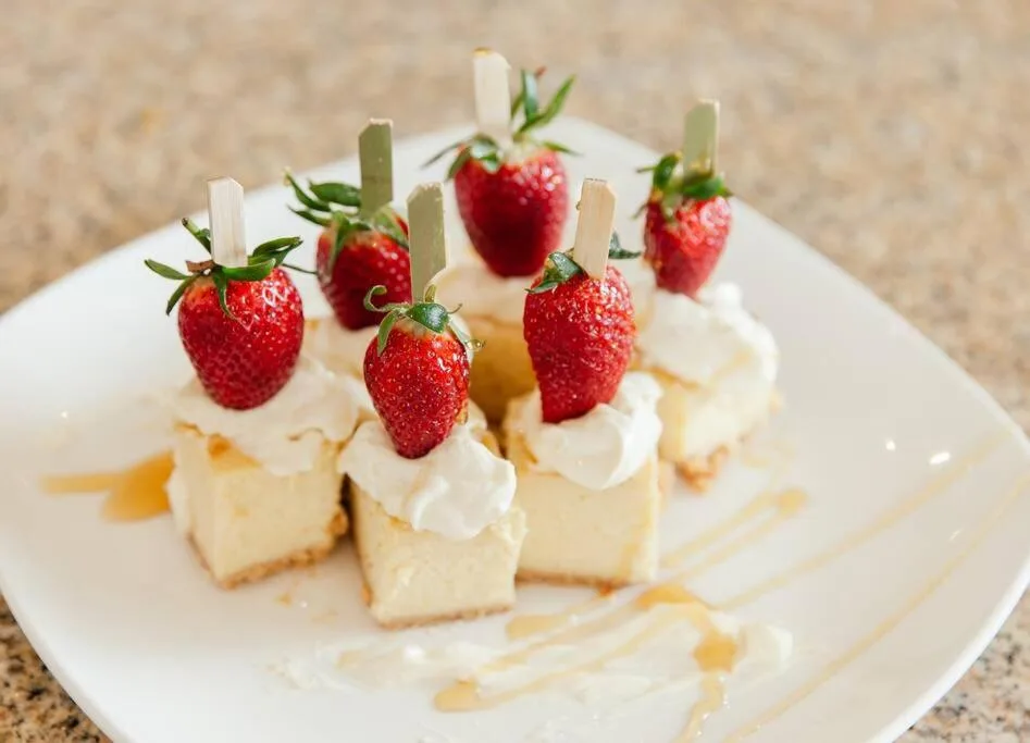Plated dessert with strawberries and cream on white plate