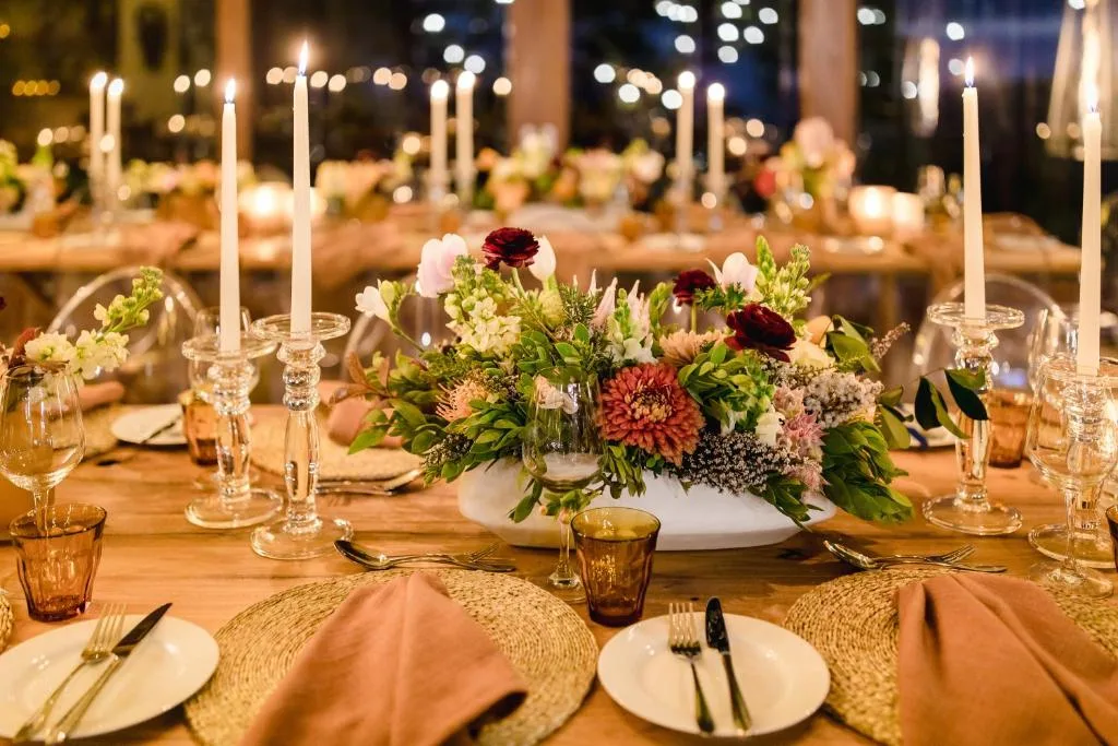 Elegantly set outdoor dining table with floral centerpieces and candlelight