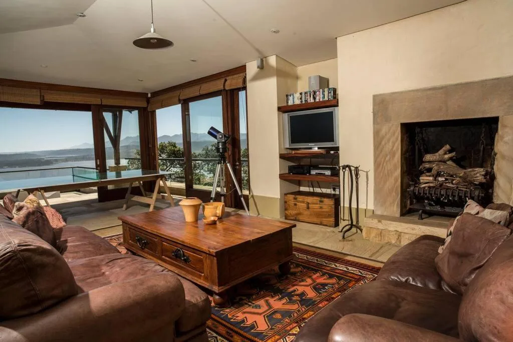 Spacious living room with leather seating, fireplace, and expansive water views