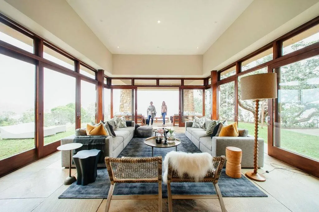 Spacious modern lounge with gray sofas, floor-to-ceiling windows, garden views
