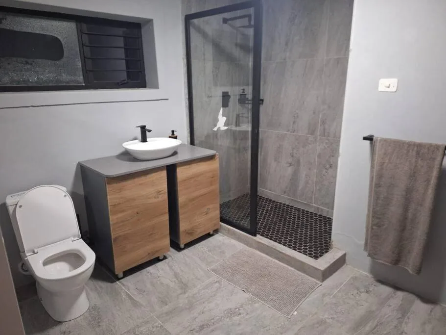 Modern bathroom with wooden vanity, round vessel sink, and walk-in shower