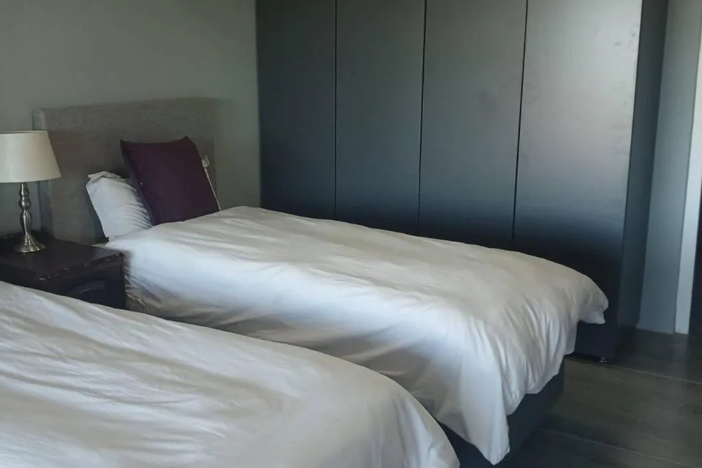 Twin beds with white linens and burgundy accent pillow in modern bedroom