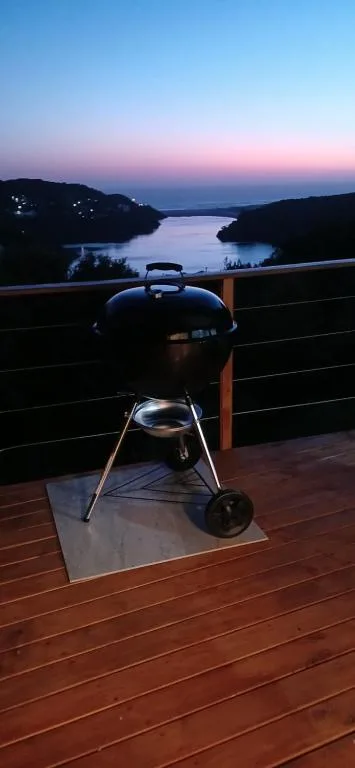 Braai grill on wooden deck overlooking lagoon at dusk