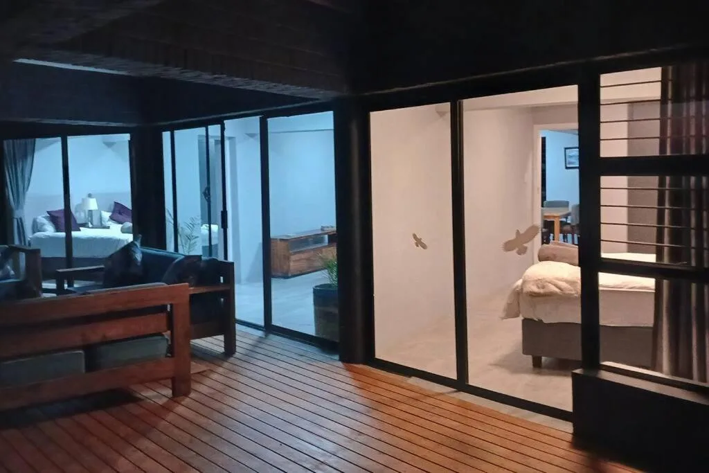 Modern wooden deck with sliding glass doors opening to bedroom and lounge areas